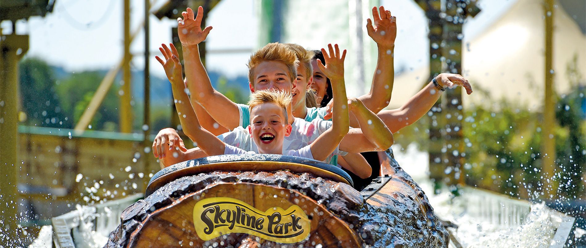 Eine Gruppe von Menschen in einem Baumstammwagen während einer spritzigen Wasserfahrt im Skyline Park.