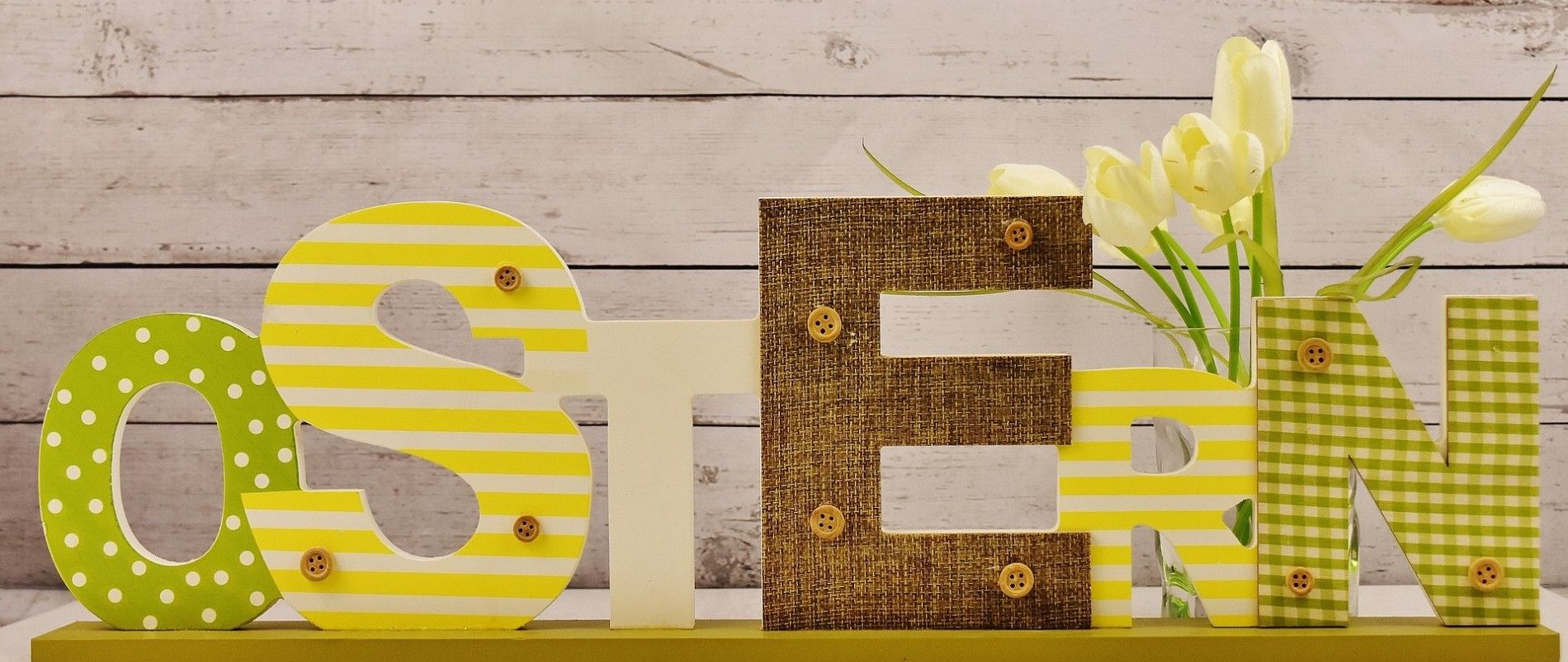 Dekoratives Schriftzug 'OSTERN' mit bunten Mustern und Tulpen.