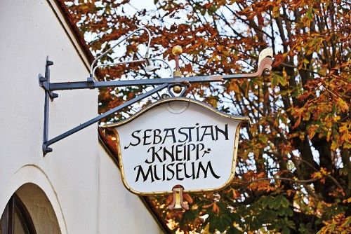Schild des Sebastian-Kneipp-Museums vor herbstlichen Bäumen.